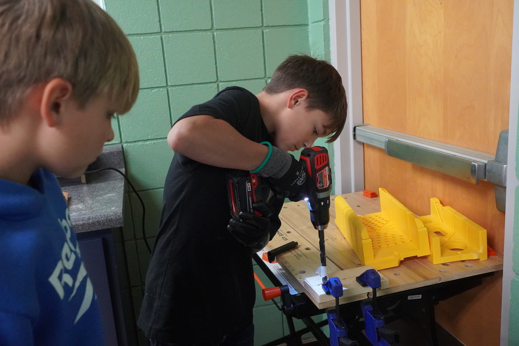 Boy student drilling a hole with a drill