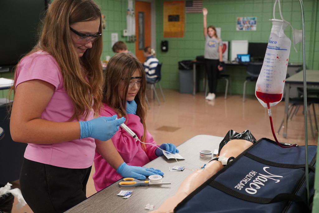 Two girls drawing blood on a dummy