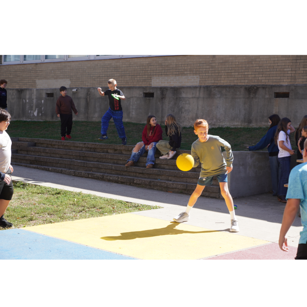 boy playing four square outside with yellow ball