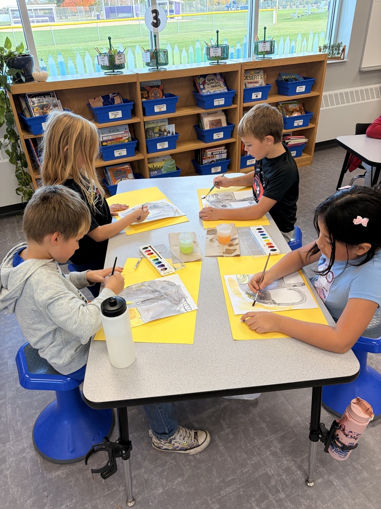 A table of students paint their Asian elephants.