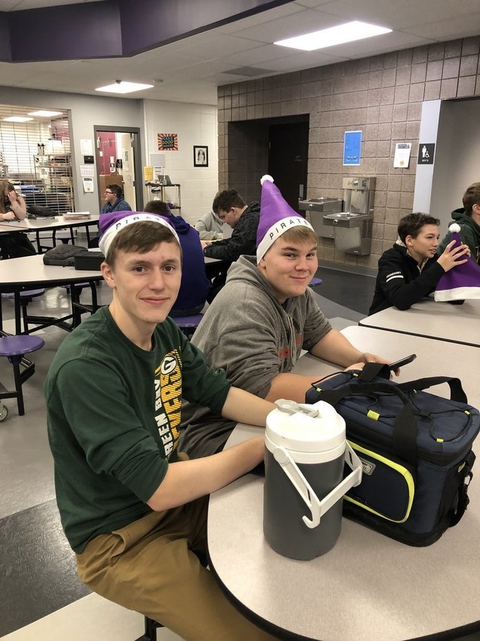 Students sitting at table with hats.