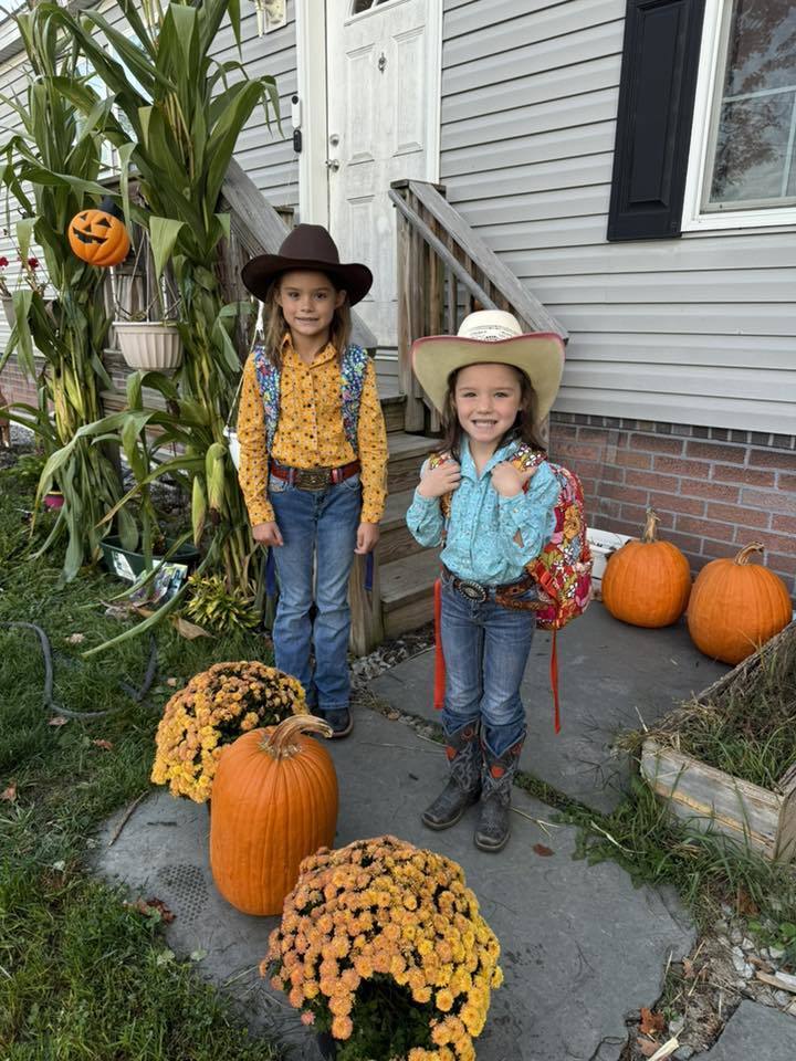 Two little girls dressed in blue and gold flannel for flannel day with fall decor all around.