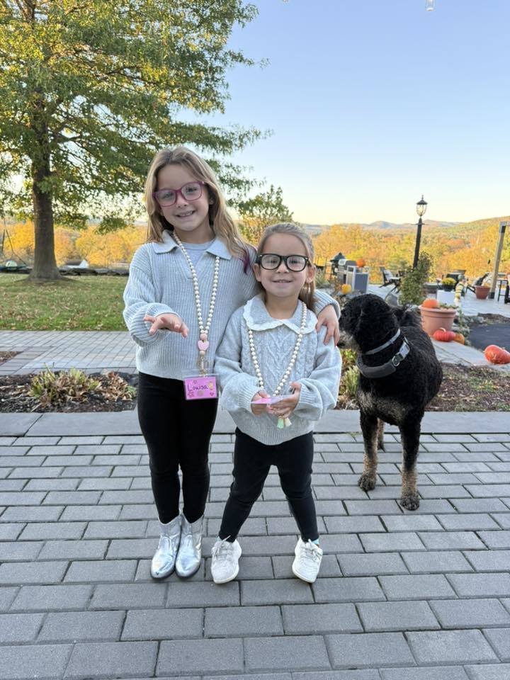 Two little girls dressed up as teachers with lanyards and glasses, sweaters and leggings