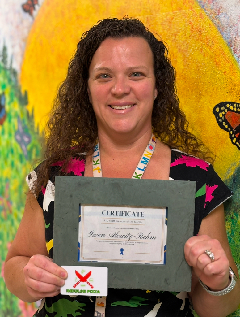 Mrs. Alowitz-Rehm 2025-2026 UPK - Holds the PTO gift frame in front of a colorful mural