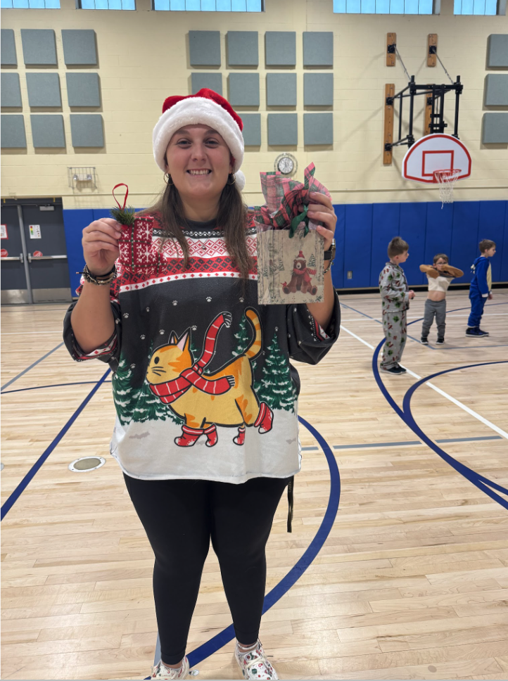 MJT P.E. Teacher, Ms. Smith in the gym with holiday ornament and gift bag