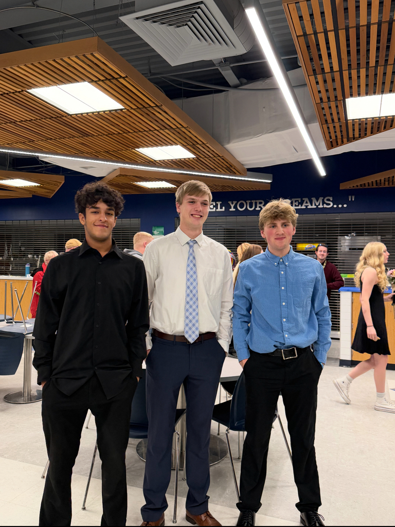 Three students standing together celebrating in the cafeteria