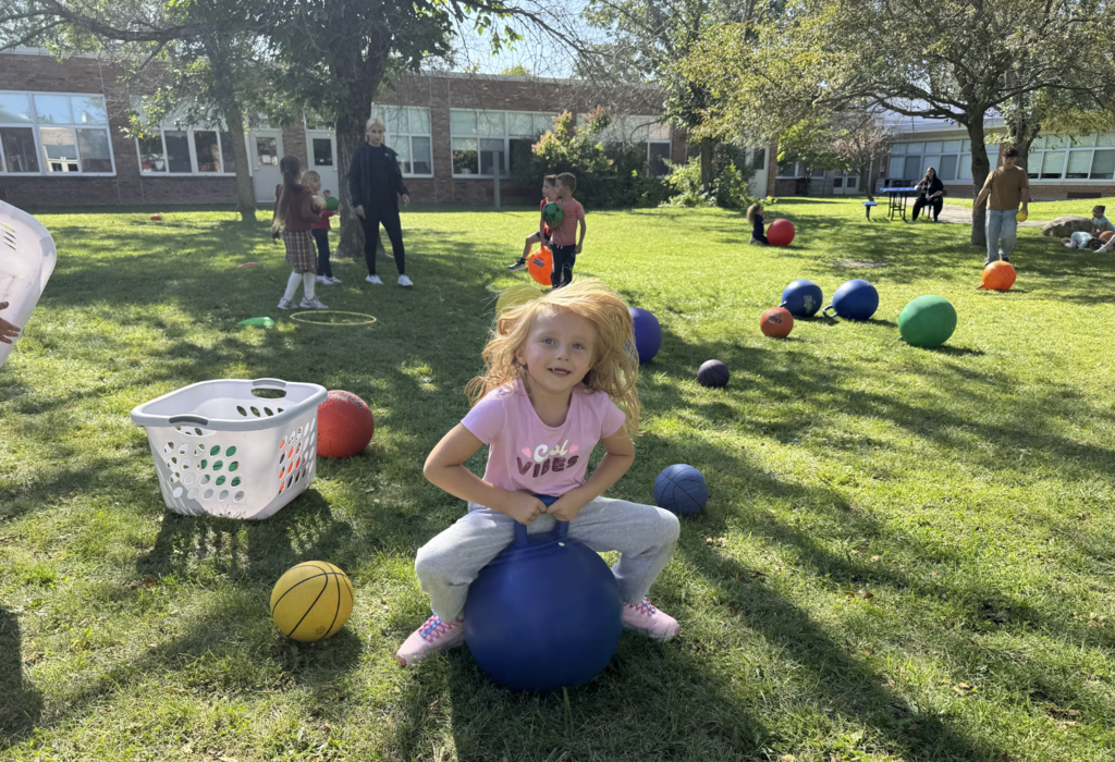 A little girl bounced on a bouncy ball seat in the outdoor courtyard of MJT school