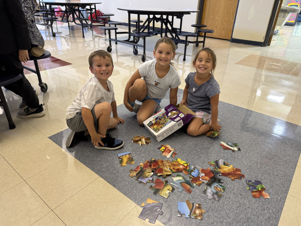 Three children play with a giant floor puzzle in the MJT afterschool program