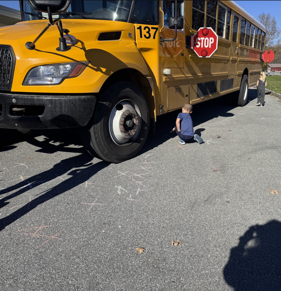 A little boy marks X for where it is unsafe to stand by a bus