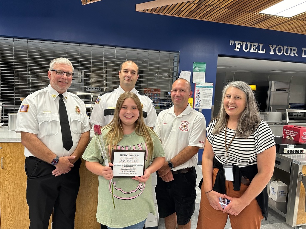 Members of the Middle Granville Fire Department and Guidance Counselor Ms. Mulvaney standing with a student receiving an award from fire department.