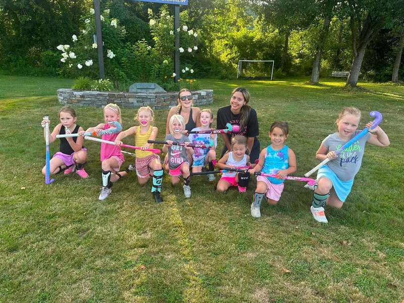 A group of field hockey youth players and two varsity players