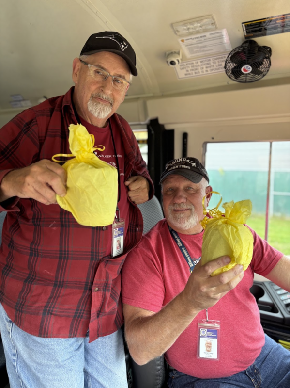 Two bus drivers hold up their gifts