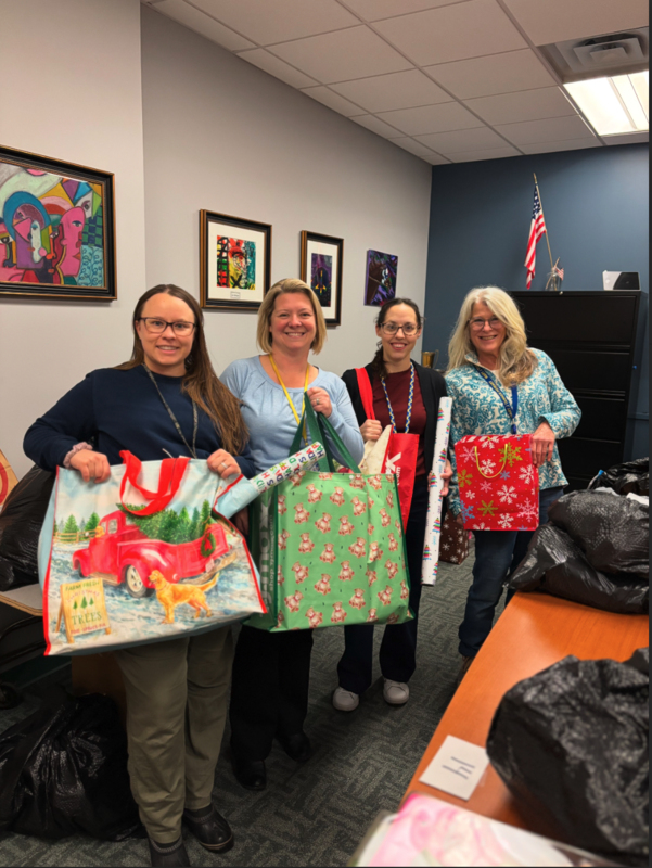 School Counselors holding holiday shopping bags for Operation Santa Claus Pick Up Day