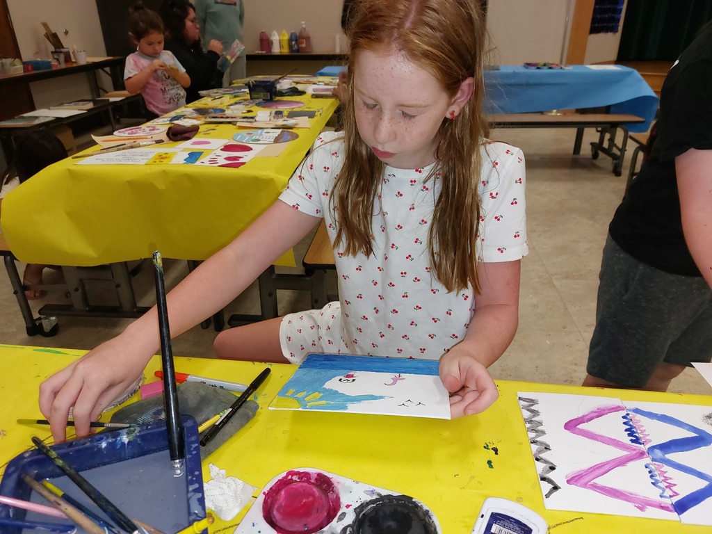 A girl looks at her partially finished painting.