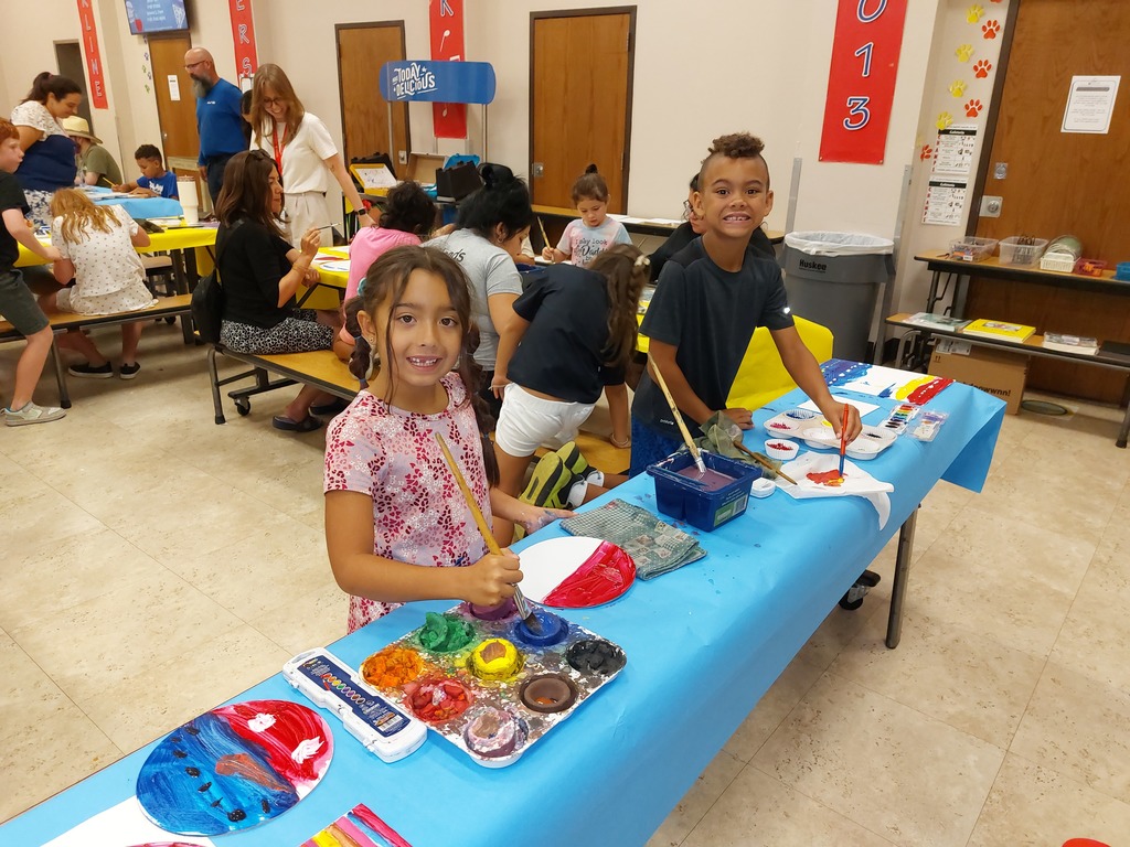A boy and girl smile at the camera from a painting station
