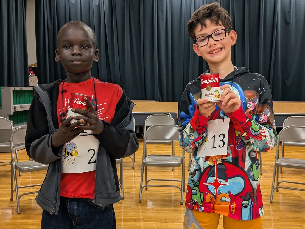 Two boys pose with cans of alphabet soup.