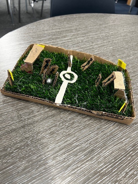 small cardboard box with fake grass, cardboard goals and soccer players