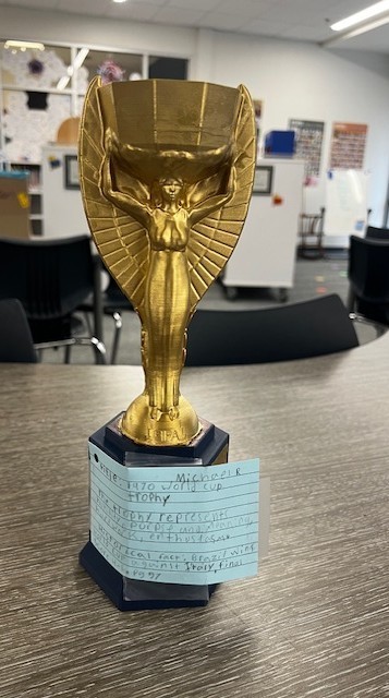 3d printed gold trophy that looks like a woman with wings and a large cup on her head