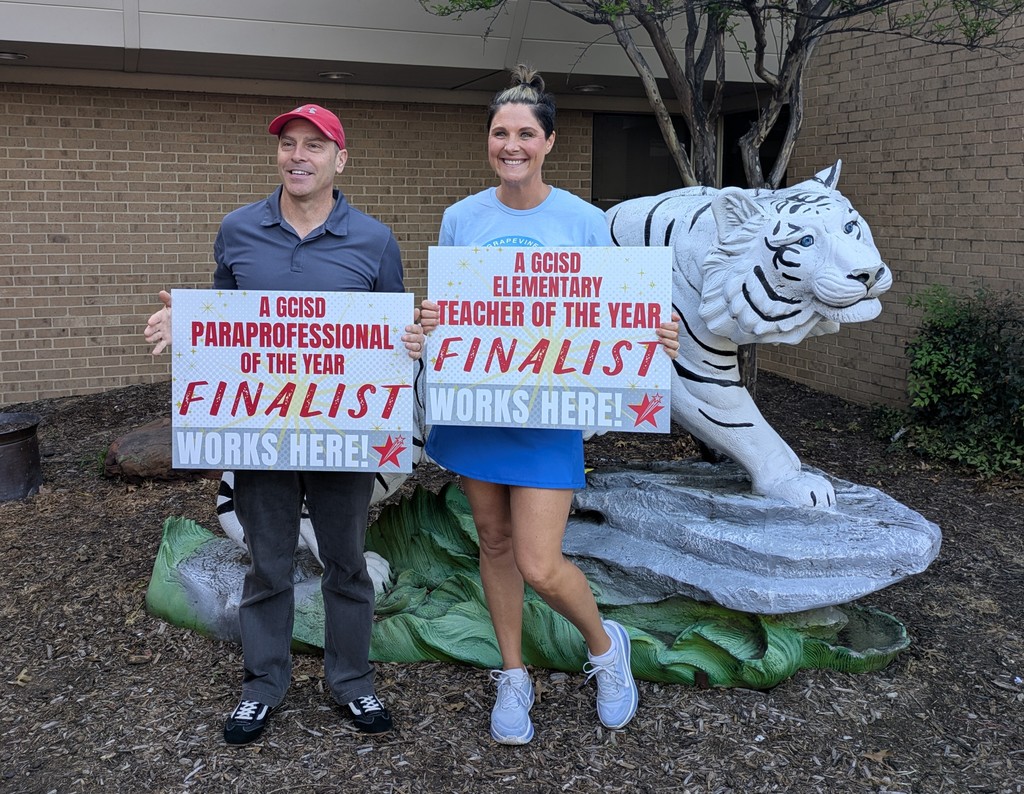 Coach Sode and Coach McDougal pose in front of the Toby statue with matching yard signs saying "Finalist for GCISD Teacher of the Year"