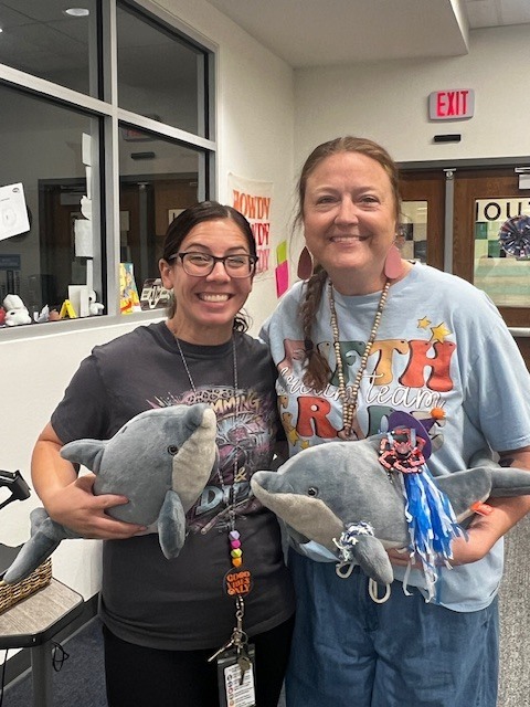two women holding stuffed dolphins