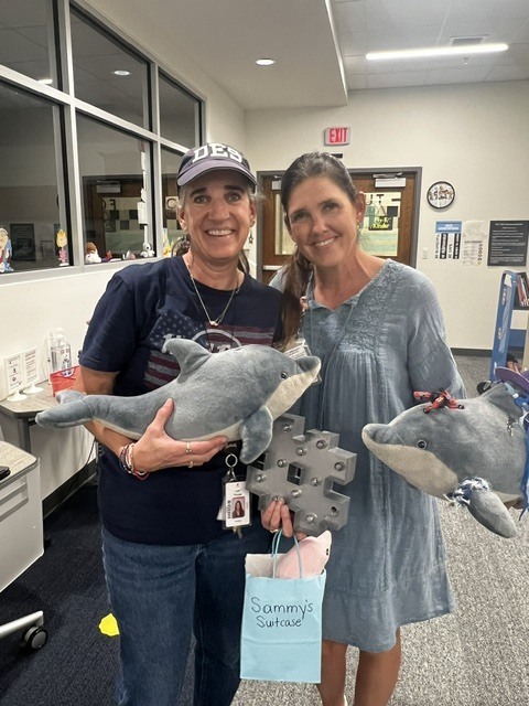 two female teachers holding stuffed dolphins