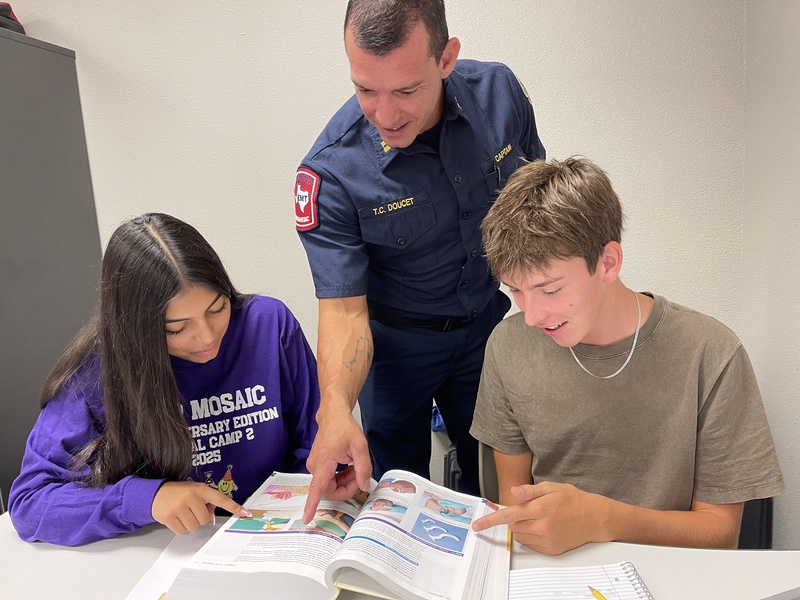 Students with firefighter looking at book