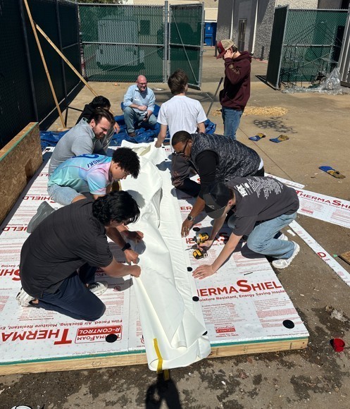 students applying roofing materials