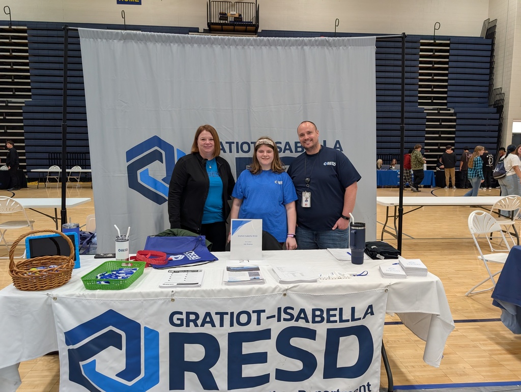 Three people standing and smiling with the GIRESD backdrop behind them