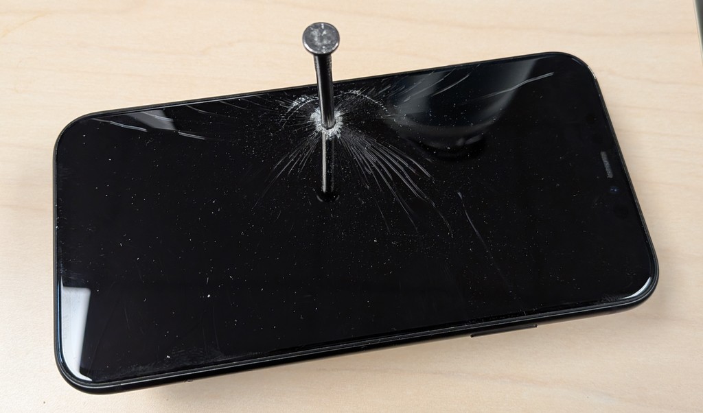 A cell phone with a nail through it.