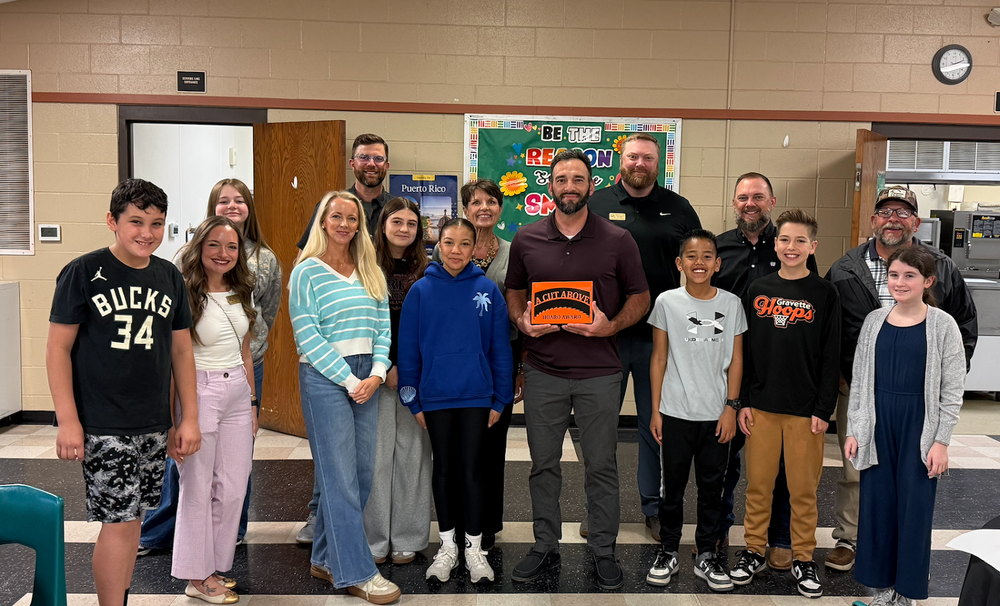 Cory Briggs holding his A Cut Above Award with the School Board and a group of students