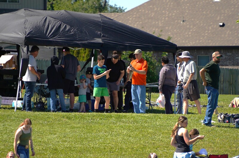 Randall Reynolds helping a student with their catch at the 2026 end-of-year fishing club derby