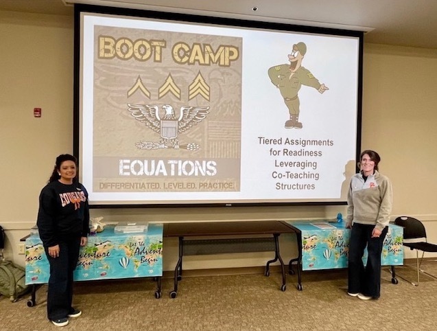 Two teachers one either side of a math boot camp image on a large screen