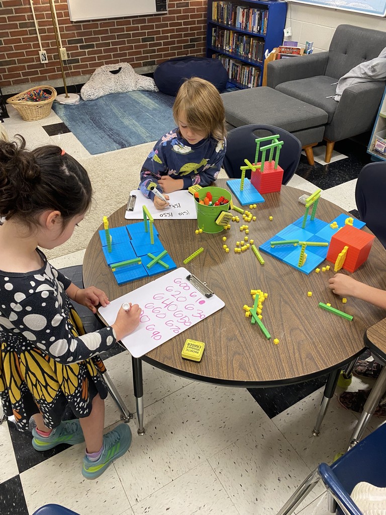 First graders working with Ms. Jen to figure out how much their base 10 builds were worth.