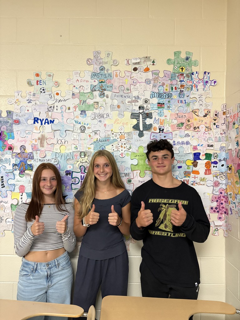 students stand in front of a wall with puzzle pieces from all classes