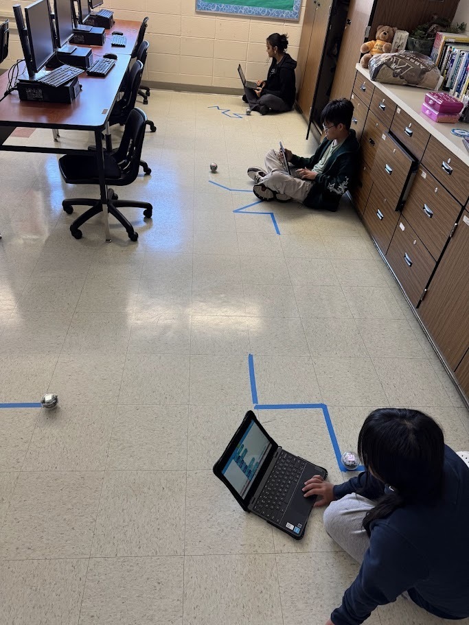 students in computer science are pictured with their chromebooks and robots