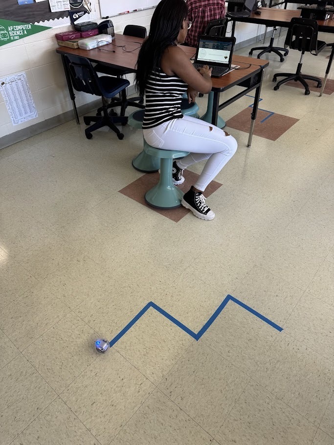 students in computer science are pictured with their chromebooks and robots