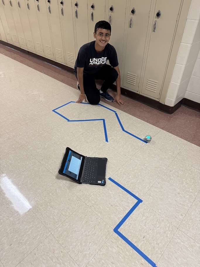 students in computer science are pictured with their chromebooks and robots