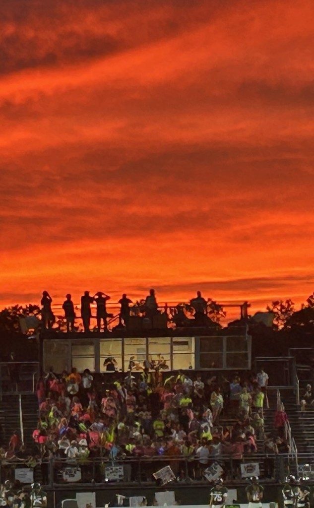 Cedar Creek student section with the backdrop of a red autumnal sunset.