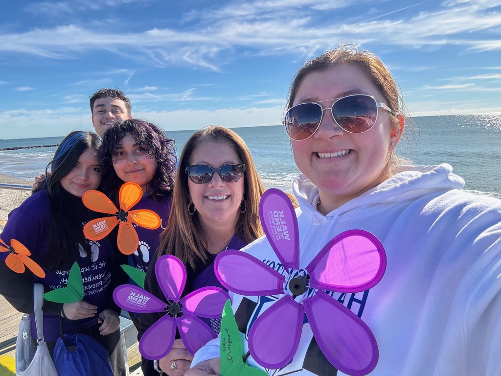 5 people standing together in front of the ocean holding flower pin wheels Absegami FBLA Team Alzheimers Walk 2025