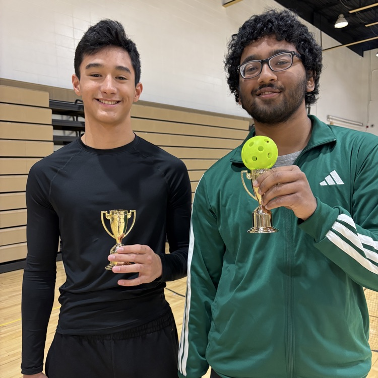two students standing with small trophies 