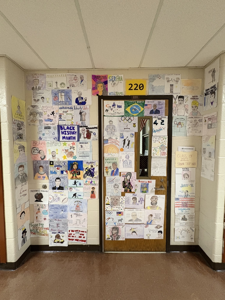 A hallway corner with a door labeled 220 and walls covered in various pictures and artwork.