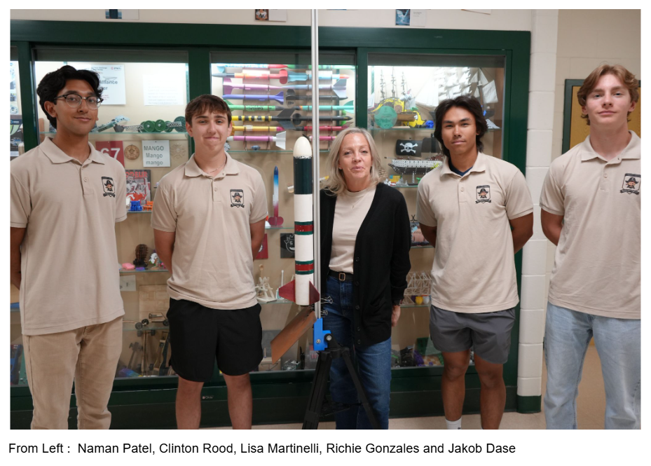 Five individuals stand together in a room. Behind them is a display case with toys.