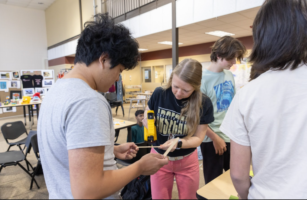 Group of students in a classroom. A person is holding and examining a tool.
