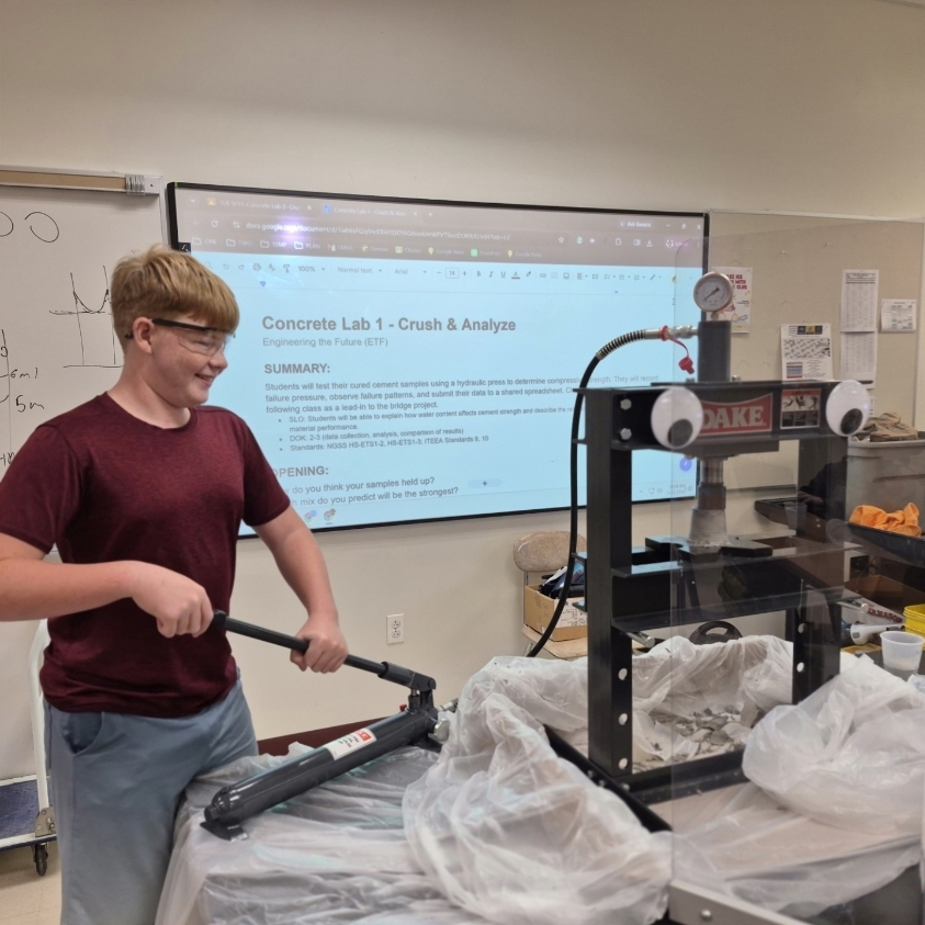 Person using a press machine while a presentation slides on the screen behind.