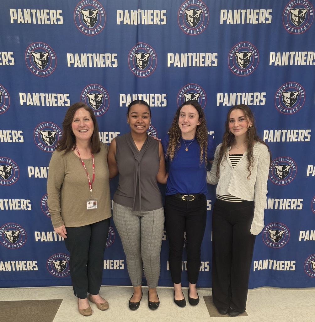 Students and a teacher standing in front of a banner