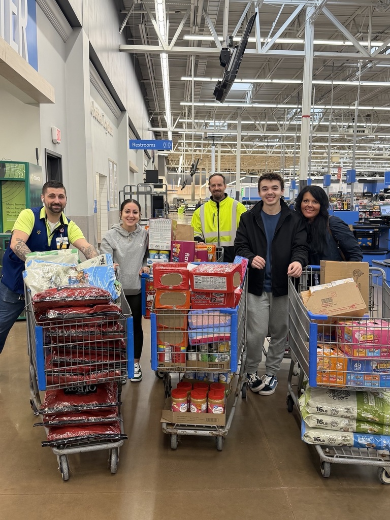 Photo of people standing behind grocery carts of goods.