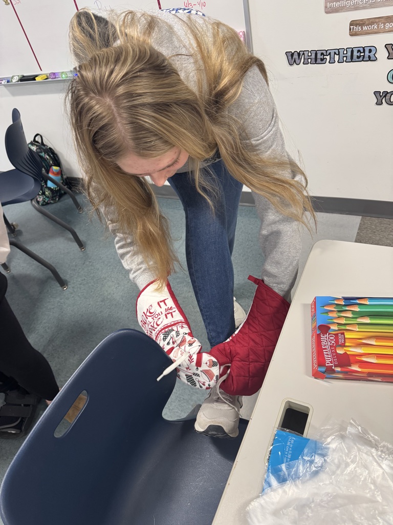 One student trying to tie her shoes with oven mits on.