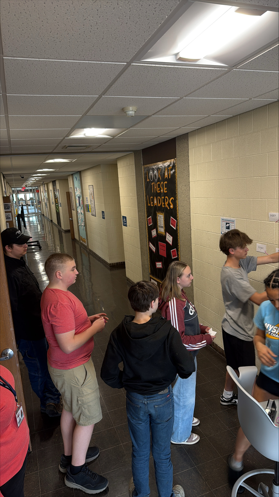 Students working together on a chain of note cards on a wall.