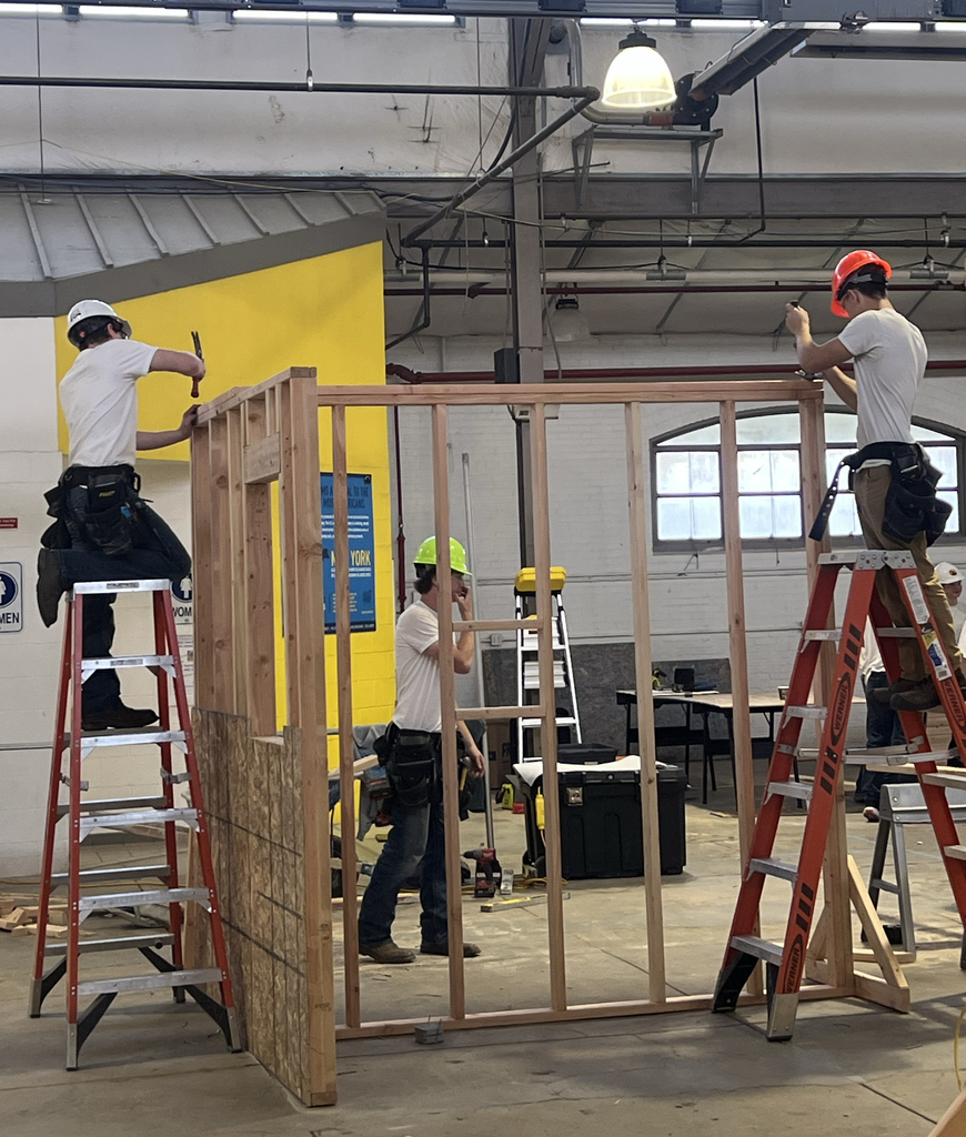 Three students in building construction setting.