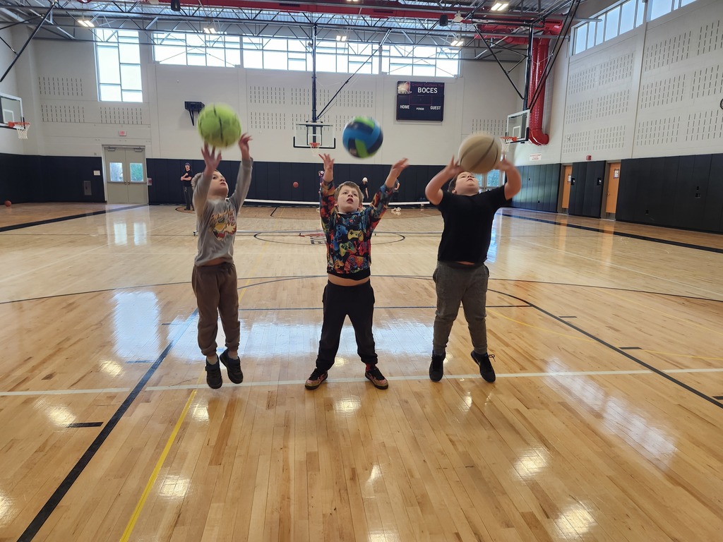 Three students learning how to shoot baskets.